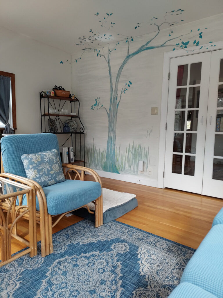 Catherine Pfuntner New Hampshire Couples Retreat Therapist's office with a large colorful tree mural on the wall and a rug on the floor.