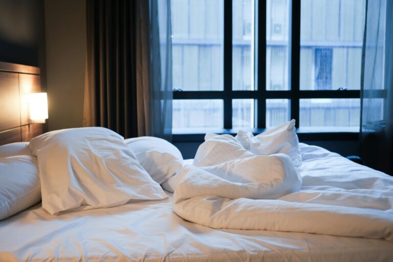 A comfortable unmade bed with white linens and pillows in a contemporary hotel setting.