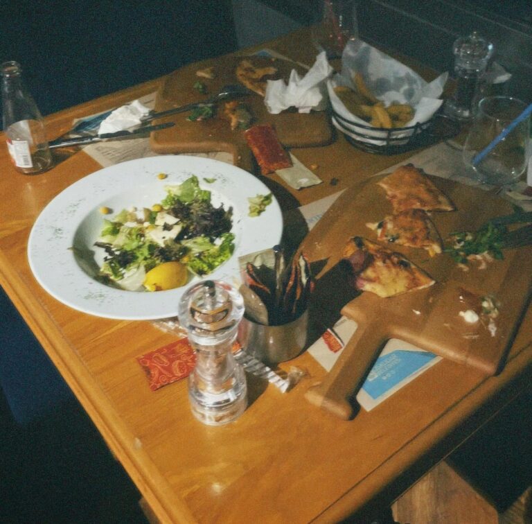 A cozy cafe table scene with remnants of a meal, including salad and appetizers.