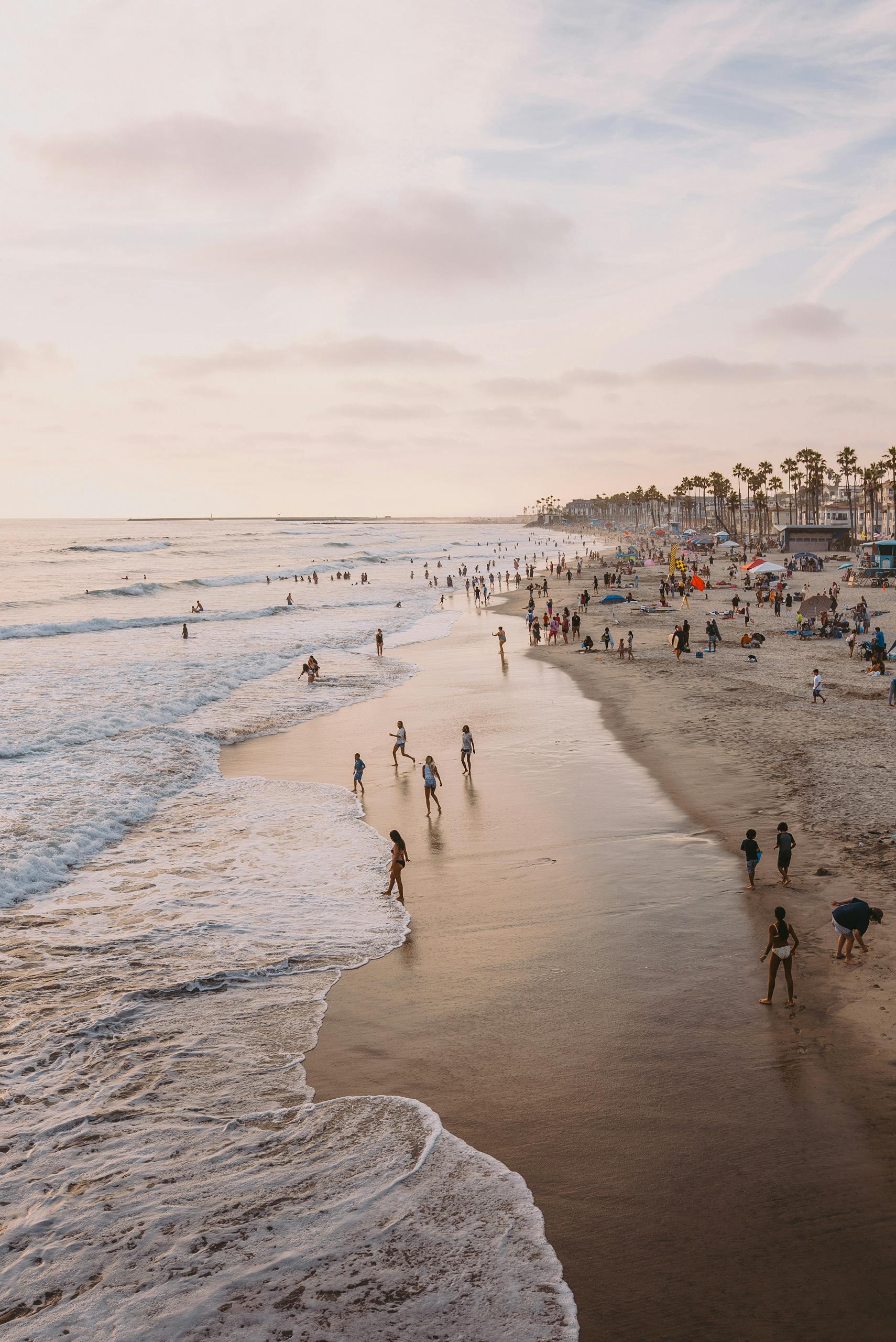A peaceful sunset beach scene with people enjoying the waves, under a calming sky.