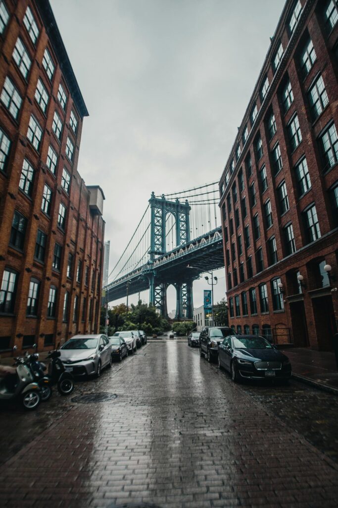 A rainy day city view capturing the iconic Manhattan Bridge framed by urban architecture in Brooklyn.