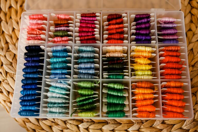 A well-organized box of vibrant embroidery threads arranged by color on a woven mat.