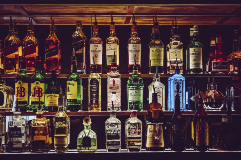 An array of various liquor bottles beautifully displayed on a bar shelf.
