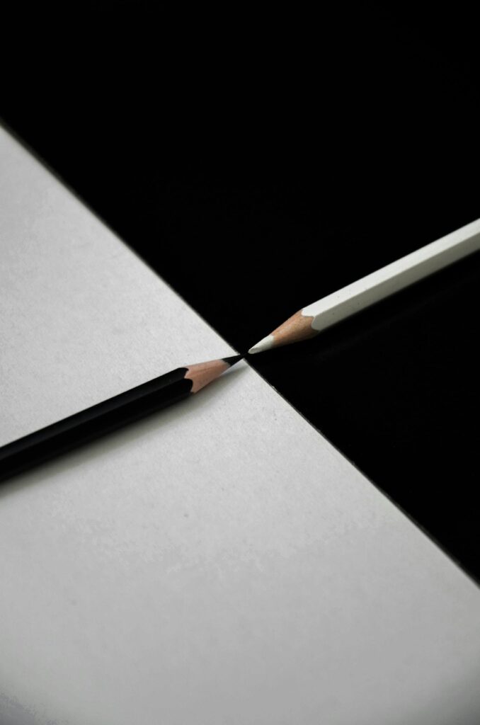 Artistic composition of black and white pencils on contrasting backgrounds.