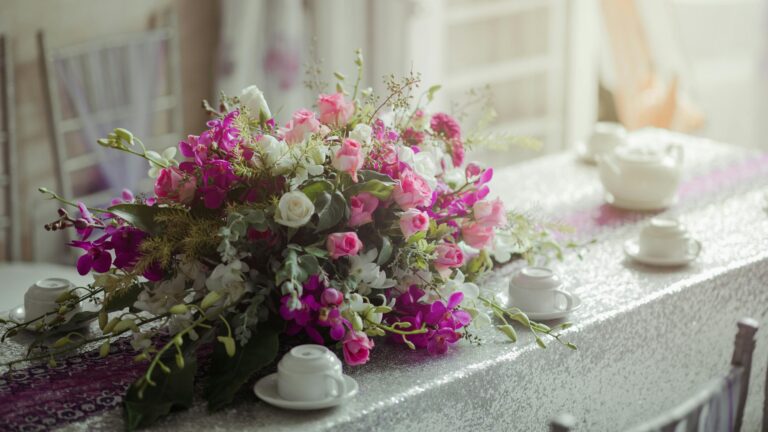 Beautiful floral arrangement with pink and white flowers on a dining table with white tea cups.