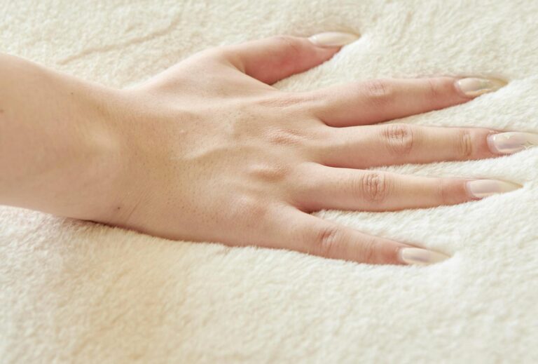 Close-up of a hand touching a soft sherpa sofa cover, displaying texture.