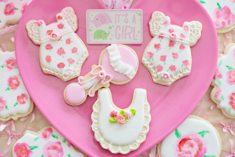 Decorated cookies for a baby girl shower with floral designs and pink accents.