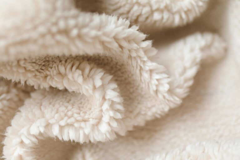 Detailed texture of a soft beige fabric blanket, showcasing fleece material.