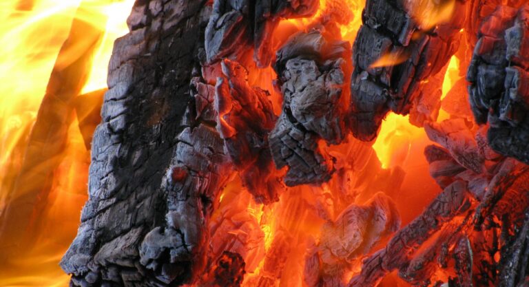 Detailed view of hot embers and flames from burning charcoal. A vibrant display of fire and heat.