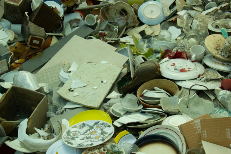 Discarded stack of broken ceramics and glassware in Gent, showcasing waste and recycling.
