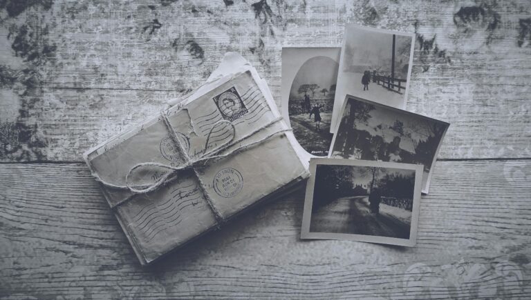 Flatlay of vintage letters tied with twine and black and white photos on a wooden surface.