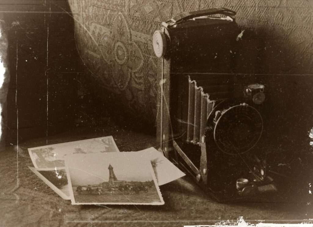 Sepia-toned image of a vintage camera with old photographs, capturing nostalgic memories.