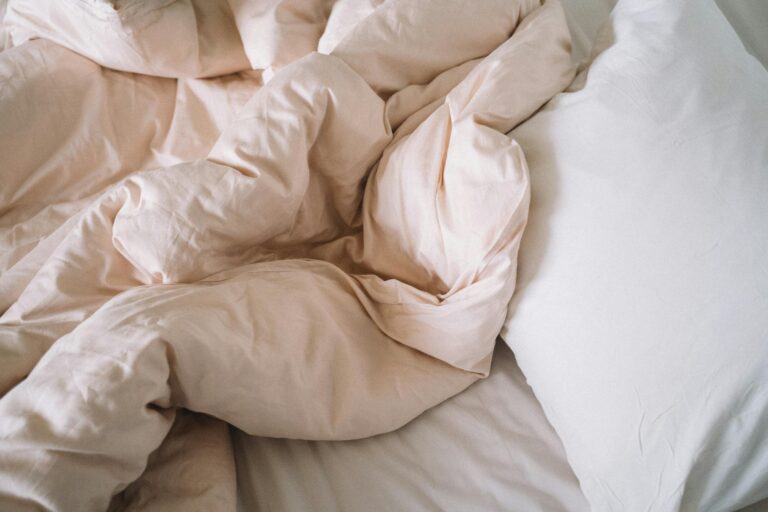 Soft crumpled bed sheets with a pillow evoke a sense of comfort and relaxation in a bedroom setting.