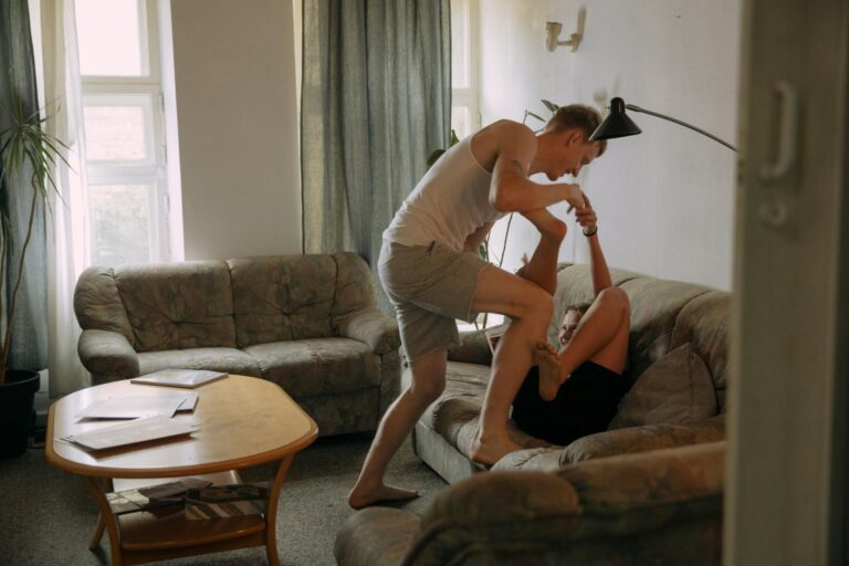 Two men enjoying playful bonding time in a comfortable living room with natural light.