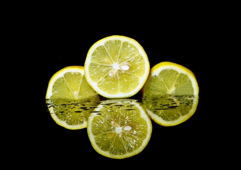 Vibrant sliced lemons with reflections on black background. Perfect for themes of freshness and health.