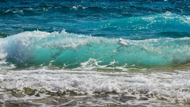 Captivating turquoise ocean waves crashing onto a sandy beach, evoking summer tranquility.