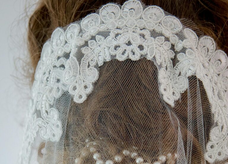 Close-up of a bride's intricate lace veil adorned with pearls, showcasing elegance and sophistication.